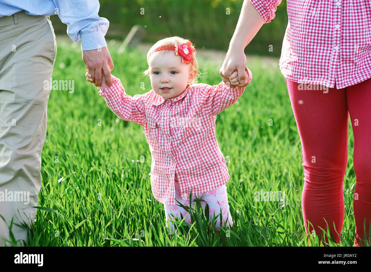 Mama und Papa und Tochter gehen auf die grünen Sommerwiese Stockfoto