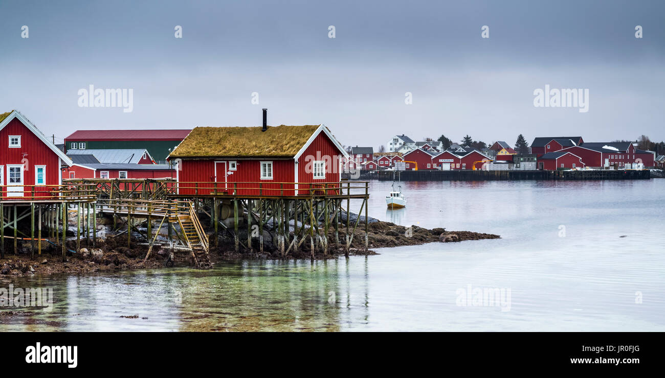 Rote Gebäude entlang des Wassers unter einem bewölkten Himmel, Lofoten, Nordland, Norwegen Stockfoto