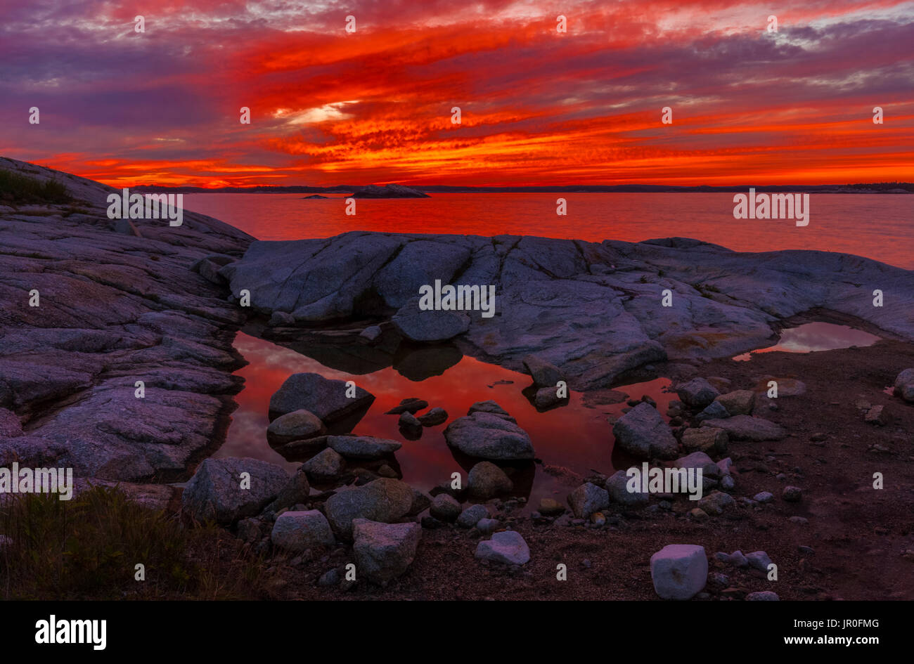 Blazing Red Himmel bei Sonnenuntergang und Blick entlang der Küste in der Nähe der Hohen Kopf Trail; Aussicht, Nova Scotia, Kanada Stockfoto