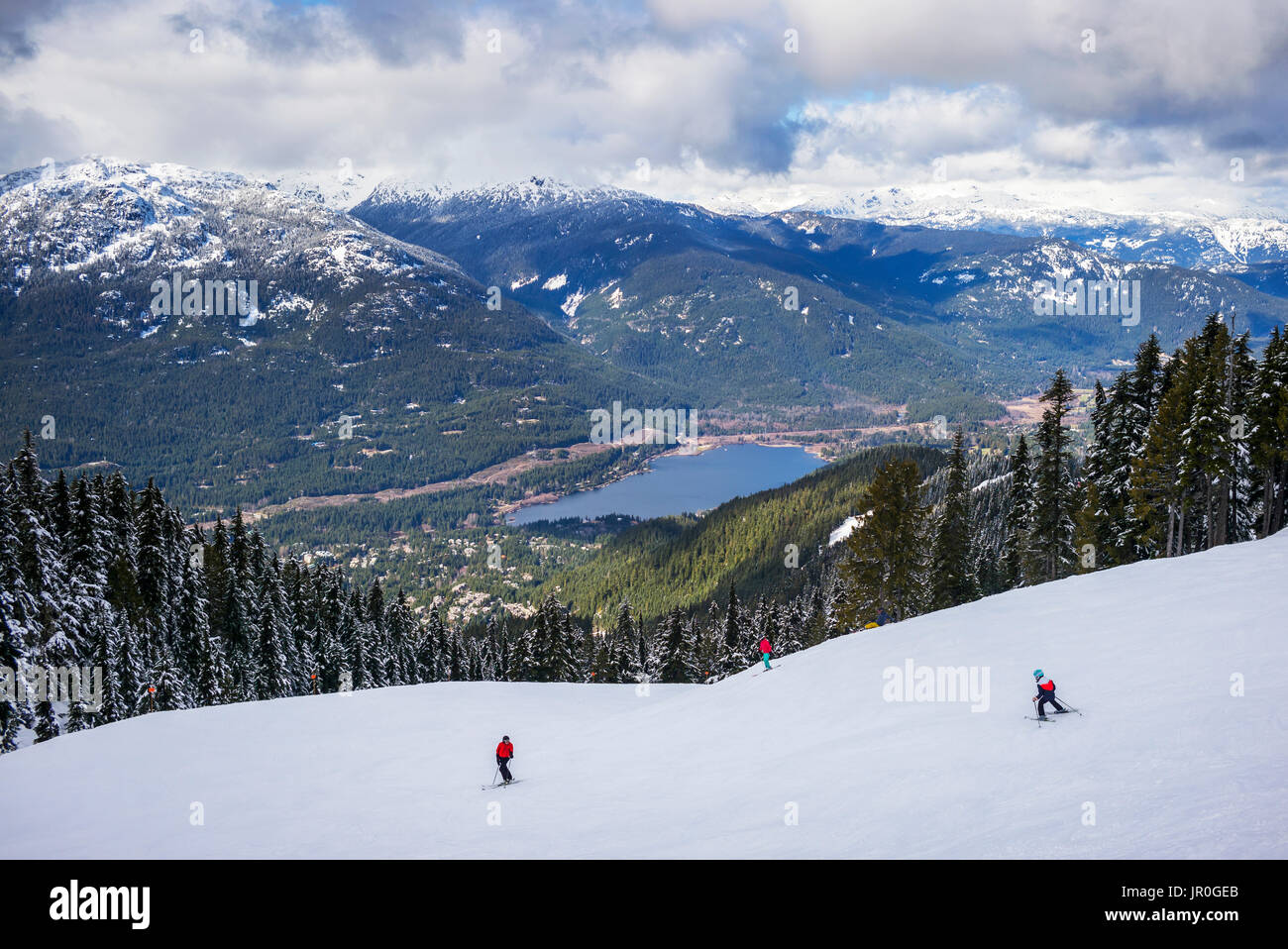 Skifahrer und Snowboarder auf dem Weg nach Unten eine Ski Hill mit herrlichem Blick auf See und in den kanadischen Rocky Mountains Stockfoto