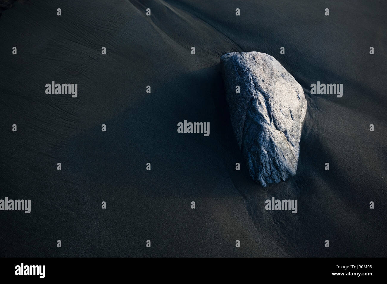 Ein Felsen sitzt auf der dunklen, nassen Sand, Alaska, Vereinigte Staaten von Amerika Stockfoto