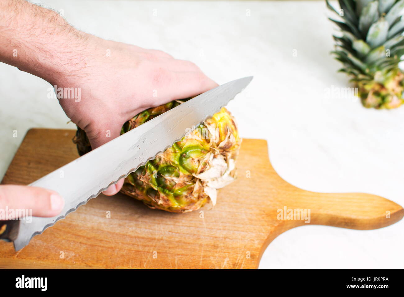 Mann schneiden Ananas Frucht auf einem Holzbrett Stockfoto
