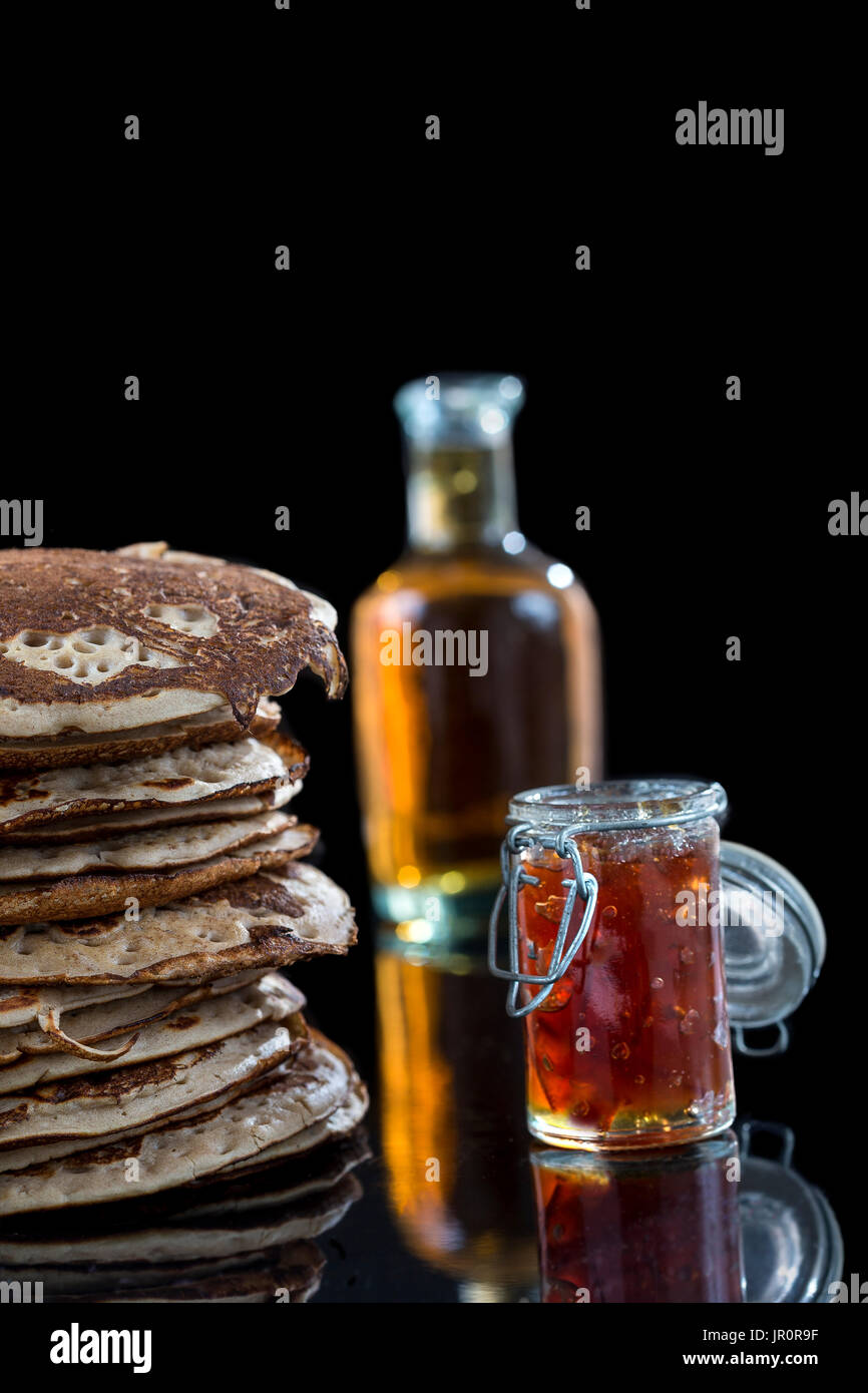 Saubere kostenlose Pfannkuchen mit Marmelade und Ahornsirup, gesunden Bio-Zutaten, auf schwarz Stockfoto