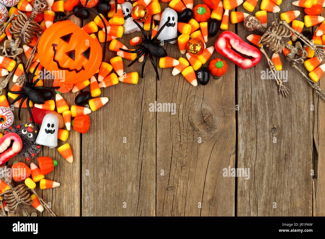 Halloween Süßigkeiten und Dekor oben Grenze vor einem rustikalen Holz Hintergrund Stockfoto