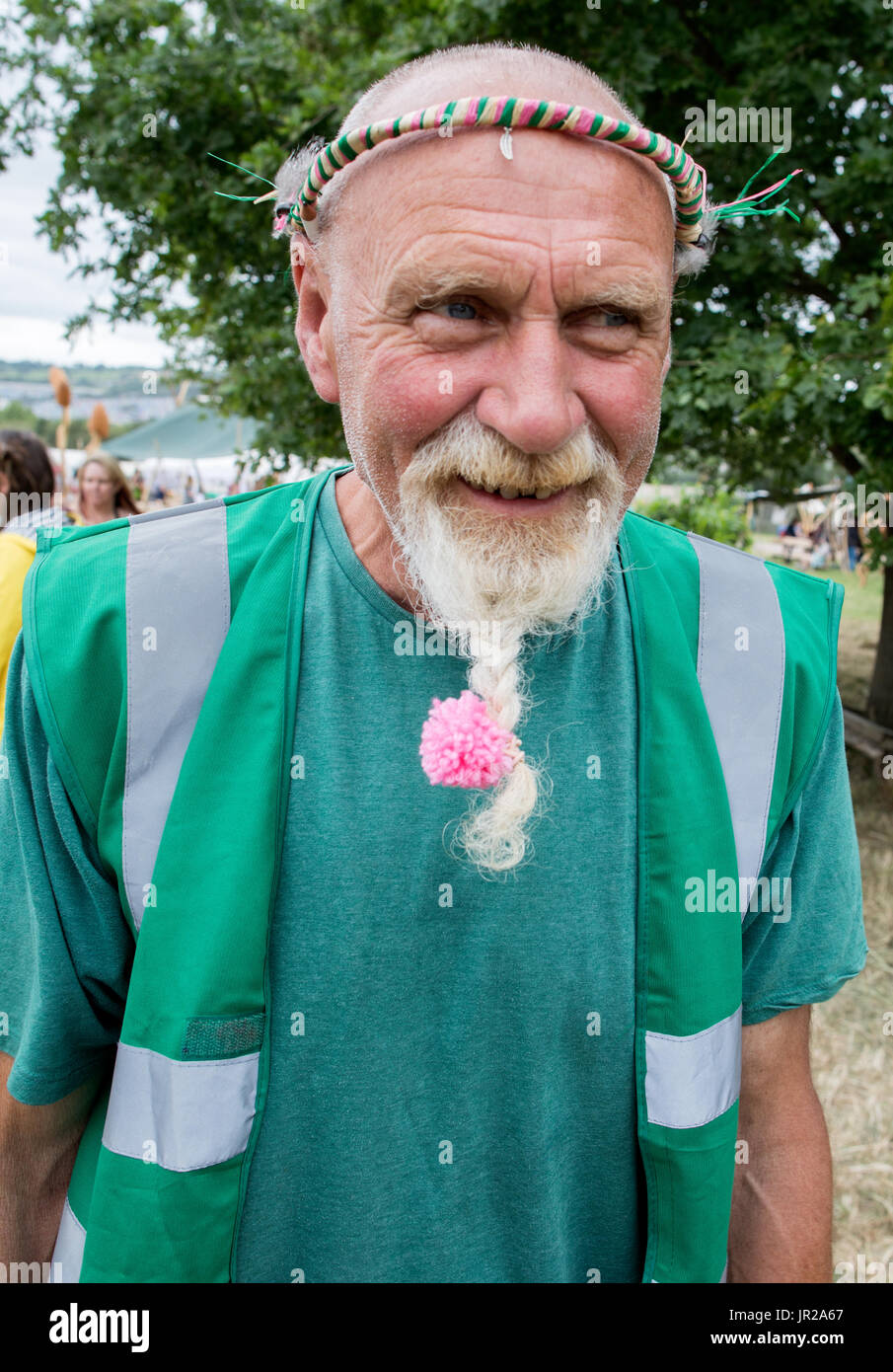 Alter Hippie mit einem rosa Blume in seinen Bart Glastonbury Festival in Großbritannien Stockfoto