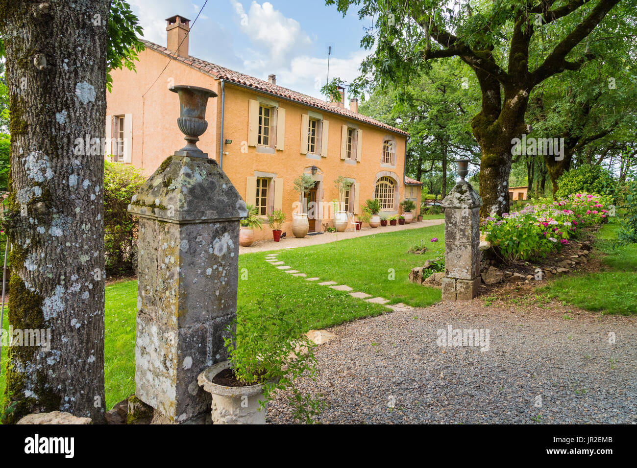 Altes Landhaus aus Stein, umgeben von ruhigen Gärten in Südfrankreich mit antikem Pfosten im Vordergrund Stockfoto