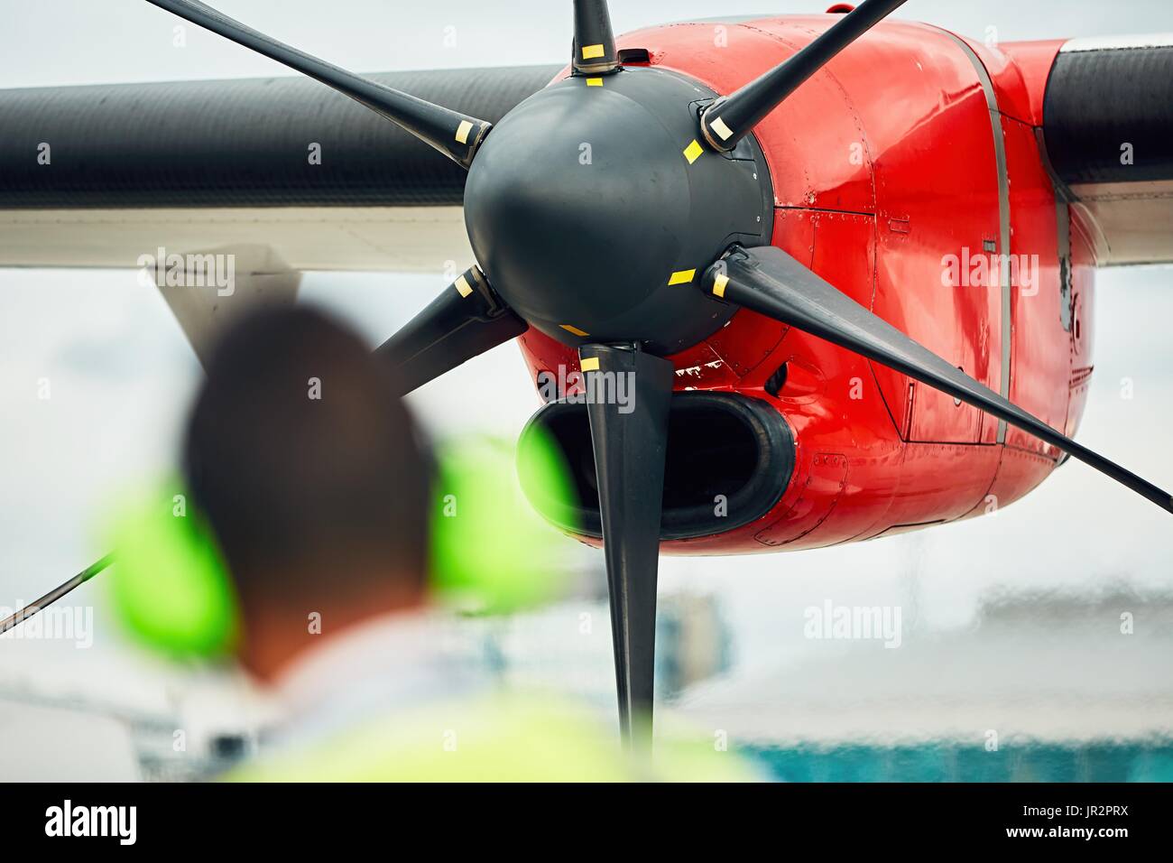 Verkehrsaufkommen auf dem Flughafen. Boden-Mitarbeiter prüft die Propellermaschine vor aus. Stockfoto