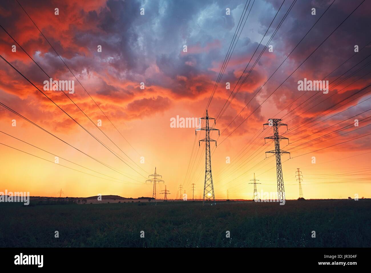 Das Wetter ist gefährlich. Strommasten mit Stromleitungen in atemberaubenden Sturm während der farbenprächtigen Sonnenuntergang. Stockfoto