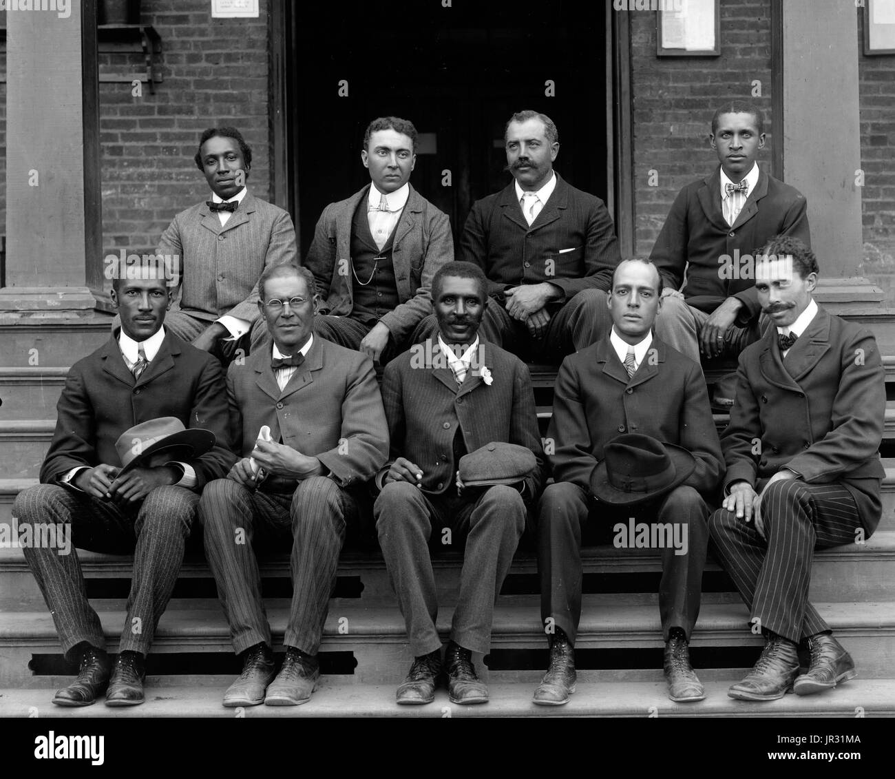 Carver, sitzend auf Schritte mit Personal am Tuskegee Institute. George Washington Carver (1864 - 5. Januar 1943) war ein afrikanisch-amerikanischer Wissenschaftler, Botaniker, Pädagoge und Erfinder in die Sklaverei hineingeboren. Im Jahre 1891 besuchte und studierte Botanik an der Iowa State Agricultural College, wo er war der erste schwarze Student und später als erster schwarzer Fakultät gelehrt. Sein Ruf basiert auf seiner Erforschung und Förderung von Alternativkulturen, Baumwolle, wie Erdnüsse, Sojabohnen und Süßkartoffeln, die auch Nahrung für die bäuerlichen Familien unterstützt. Er wollte, dass arme Bauern, beide alternative Kulturen wachsen Stockfoto