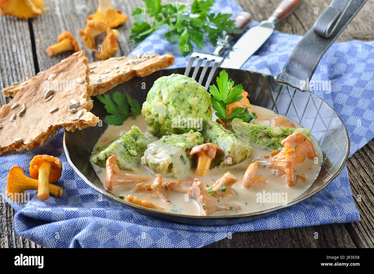 Frische Pfifferlinge mit Sahnesoße und Spinat-Semmelknödel in einer Pfanne erhitzen Stockfoto