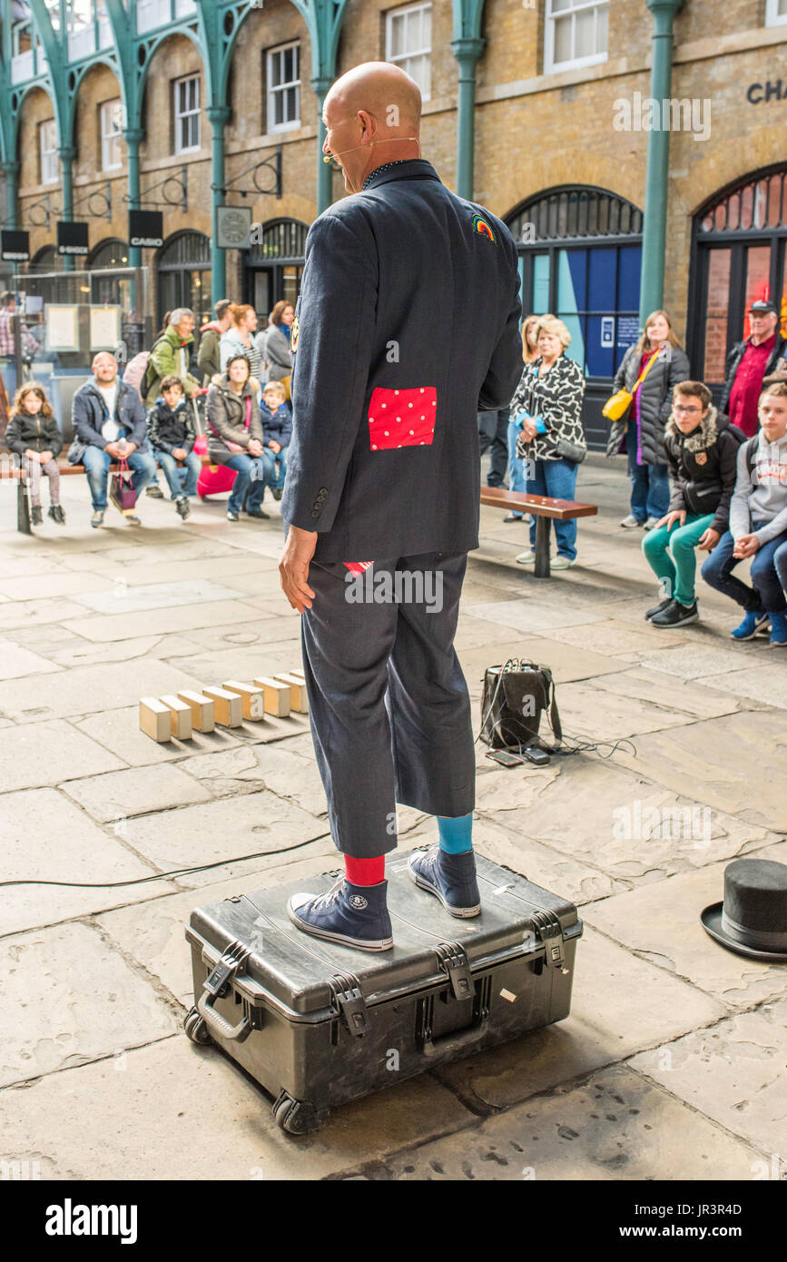 Eine street Entertainer Durchführung innerhalb des berühmten Covent Garden, London, UK, vor einer Masse von Erwachsenen und Kindern. Stockfoto