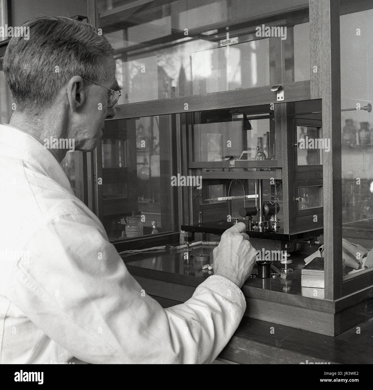 1950, historische, männliche Wissenschaftler in einem mit einer mikrowaage labatory, ein Instrument für die präzise Messung von sehr kleinen Gewichte verwendet, Universität Oxford, Oxford, England, UK. Stockfoto