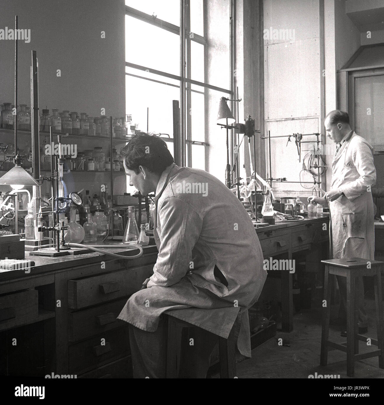 1950, historische, männliche Wissenschaftler in einem Labor Experimente durchführen, an einer hölzernen Werkbank, England, UK. Stockfoto