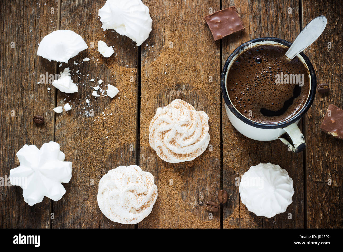weiße Baiser auf dunklem Holz Hintergrund mit Retro-Metall Kaffeetasse Stockfoto