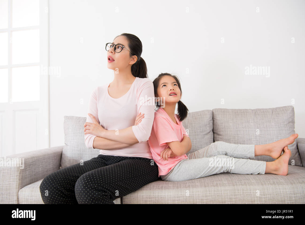 junge Hausfrau mit niedlichen kleinen Mädchen machen tagsüber Tagträumen auf Urlaub zu Hause beobachten, dass Luft denken hat einige großartige Idee, die sitzen auf dem Sofa in t Stockfoto