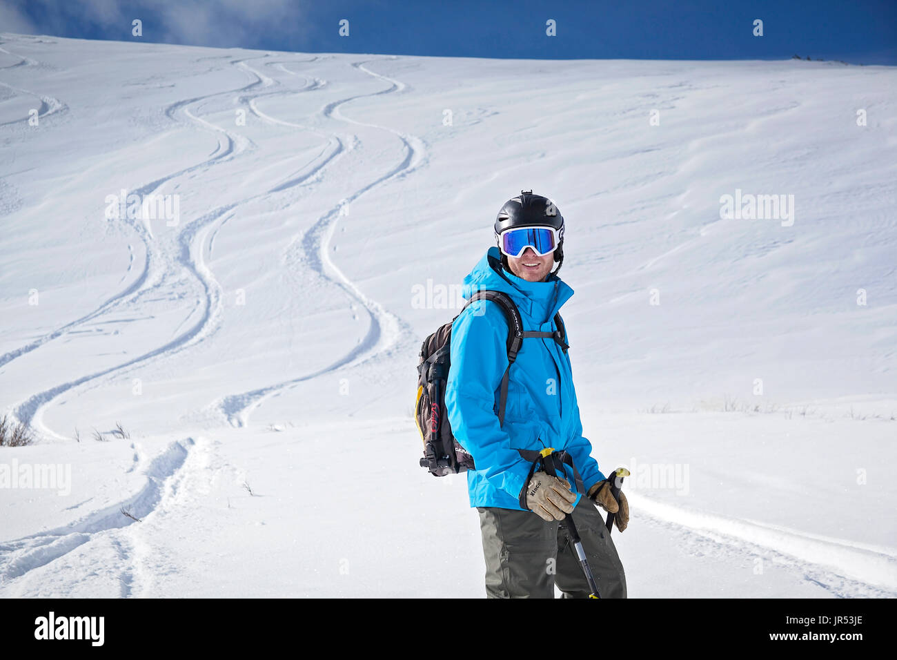 Backcountry Skifahrer mit Lächeln mit frischen Spuren im Hintergrund Stockfoto