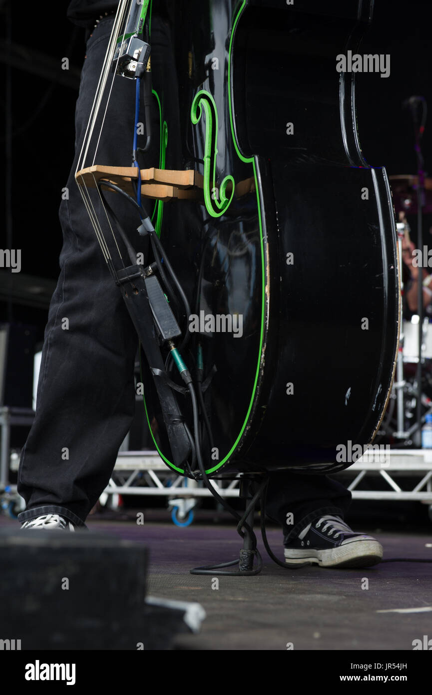 Double Bass Player tragen converse Schuhe spielen live auf der Bühne bei Coventry Godiva Music Festival, Coventry, Großbritannien. Stockfoto