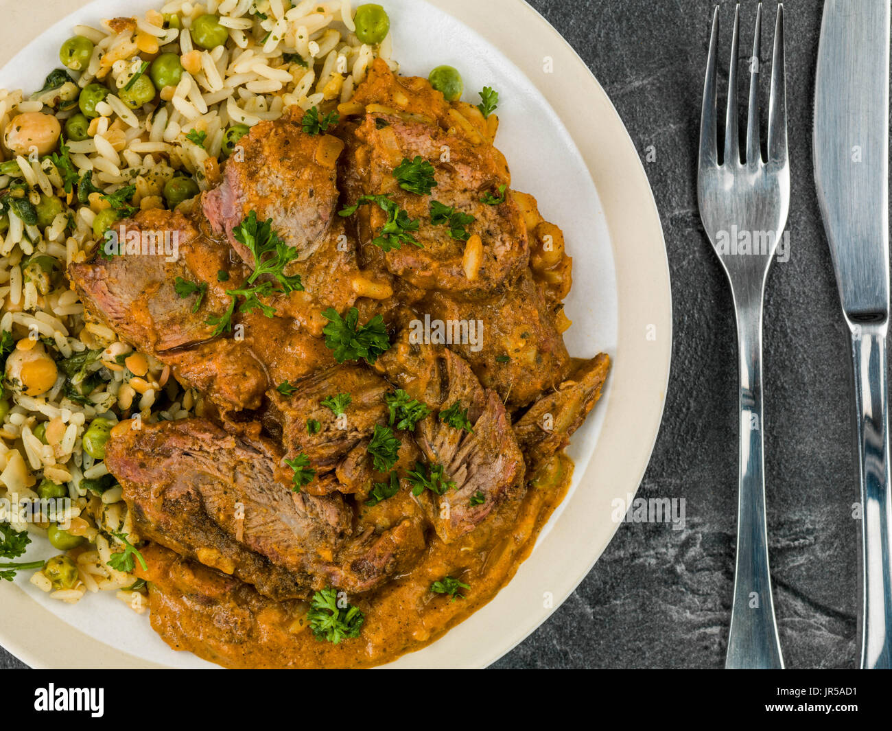 Aromatisches Lammcurry mit Gemüsereis Hintergrund schwarzen Schiefer Fliesen Stockfoto