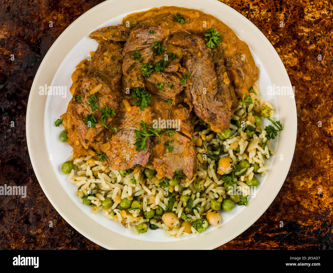 Aromatisches Lammcurry mit Gemüsereis gegen eine notleidende Backblech Stockfoto
