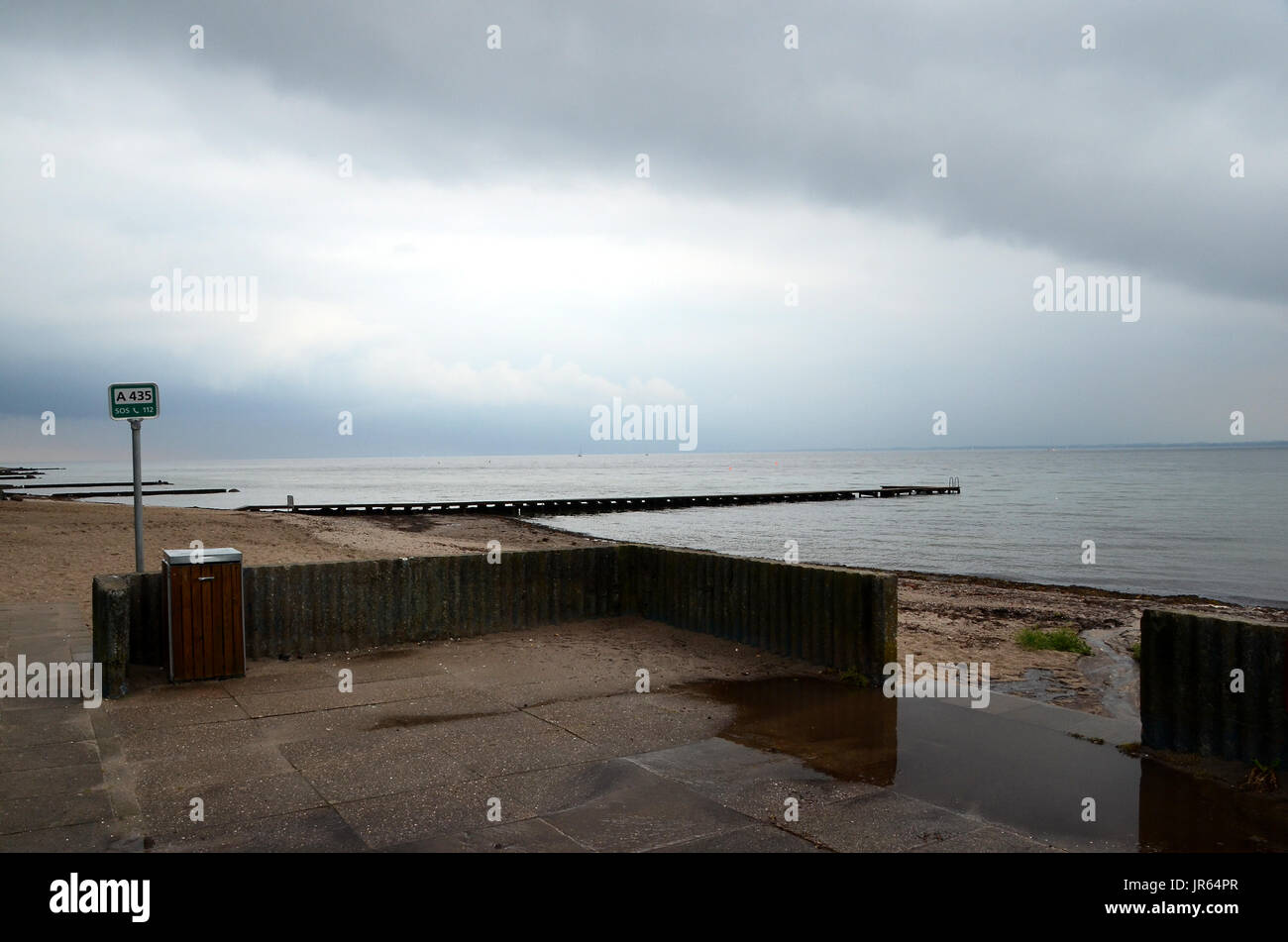 Leere Badestrand bei regnerischem Wetter, mit mehr Regen in den Horizont. Stockfoto