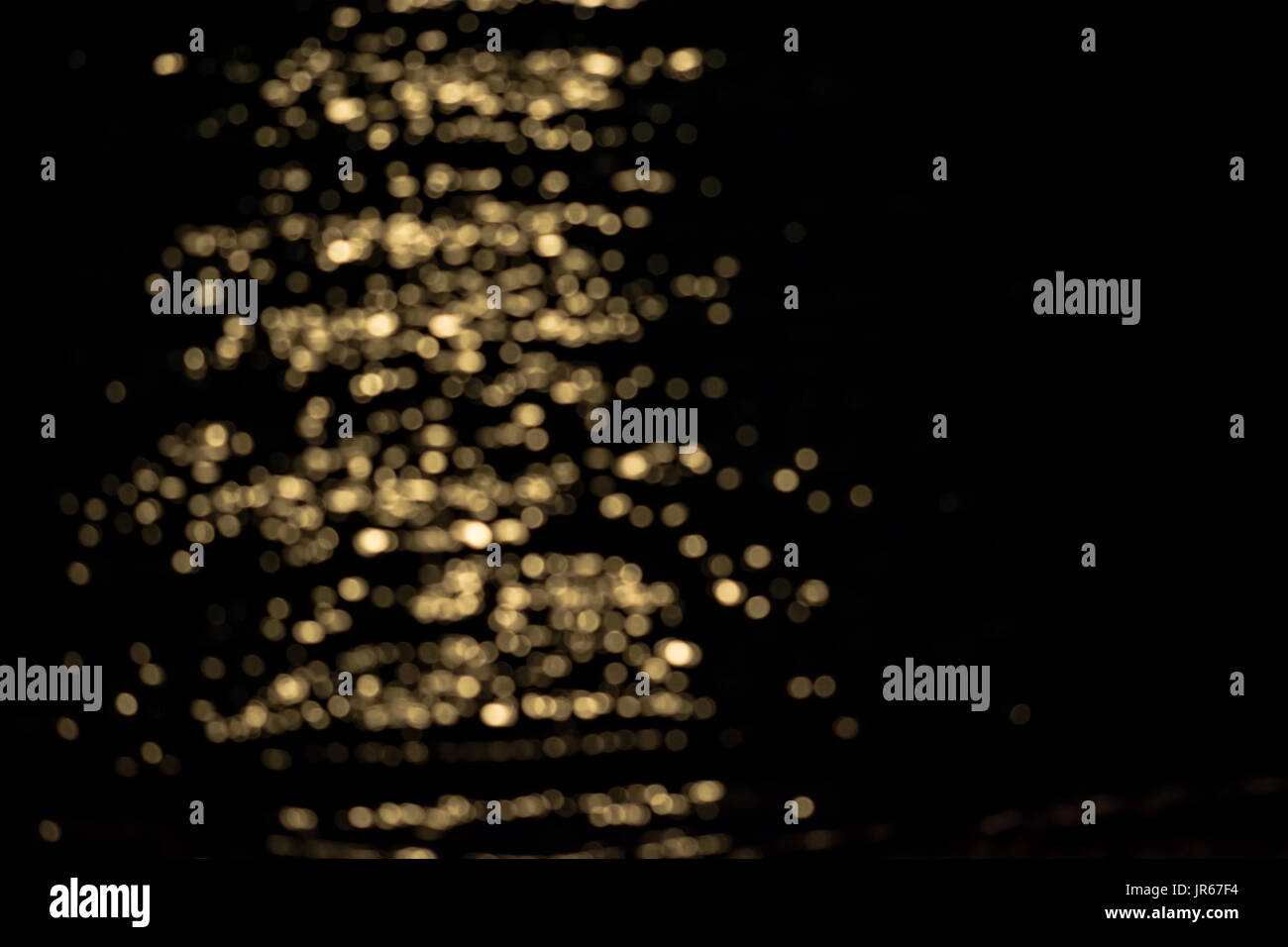 Defokussierten Reflexion einer gelben Lichtquelle über dem Wasser, die Erstellung eines Musters der Lichtblicke Stockfoto
