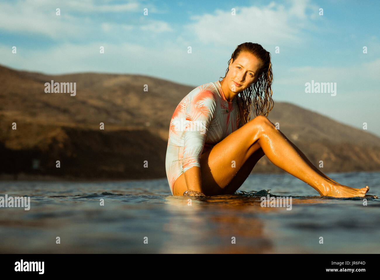 Frau sitzt auf einem Surfbrett im Ozean, Malibu, California, Amerika, USA Stockfoto