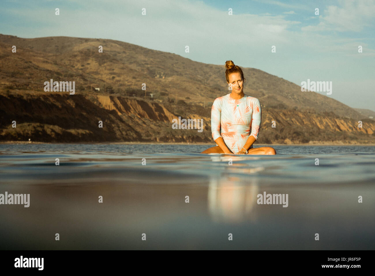 Frau sitzt auf Surfbrett im Ozean, California, Amerika, USA Stockfoto