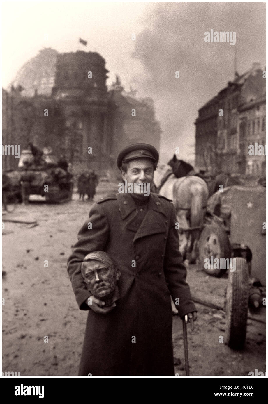 REICHSKANZLERIN REICHSTAG WW2 NAZI-NIEDERLAGE RUSSISCHER SOLDAT HITLER BUST BERLIN 1945 russische BESETZUNG ein glücklicher sowjetischer russischer Soldat, der eine Büste des „Führers“ Adolf Hitler trug, holte sich im Hintergrund aus den Ruinen des deutschen Reichskanzlergebäudes im Berliner Reich zurück, das auf die überwältigende sowjetische Militärstreitkraft fiel, Mai 2. 1945 Stockfoto