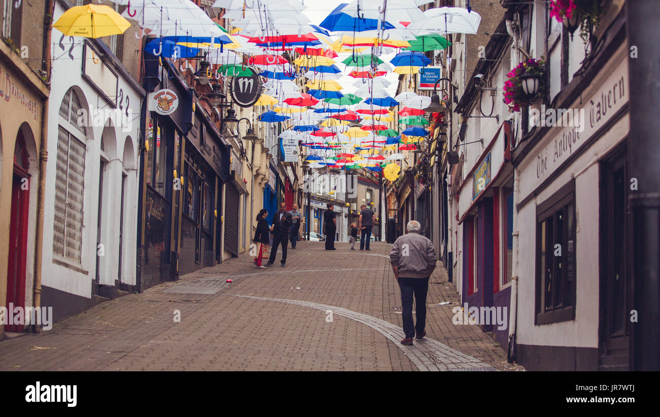 Menschen zu Fuß durch die Straße in Enniscorthy, Irland mit schwebenden Sonnenschirme für den Rockin' Food Festival eingerichtet Stockfoto