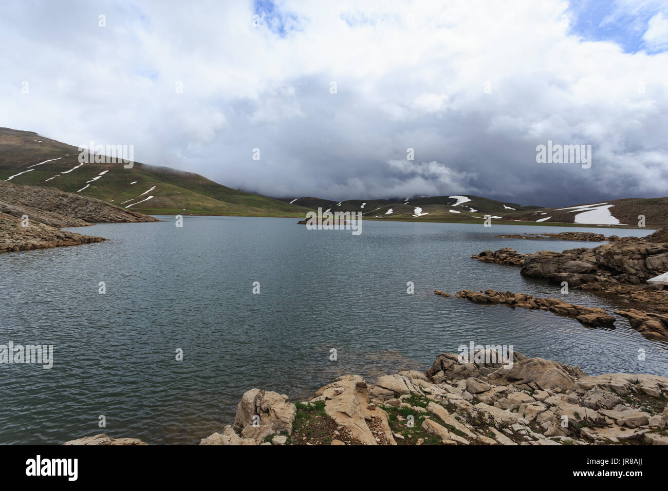 Horizontalen Schuss von Mountain Lake umgeben von Pisten fallenden Schnee schmelzen Stockfoto