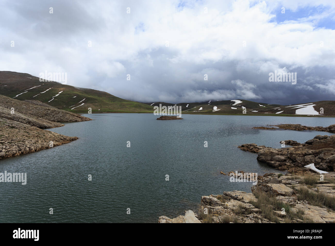 Horizontalen Schuss von Mountain Lake umgeben von Pisten fallenden Schnee schmelzen Stockfoto