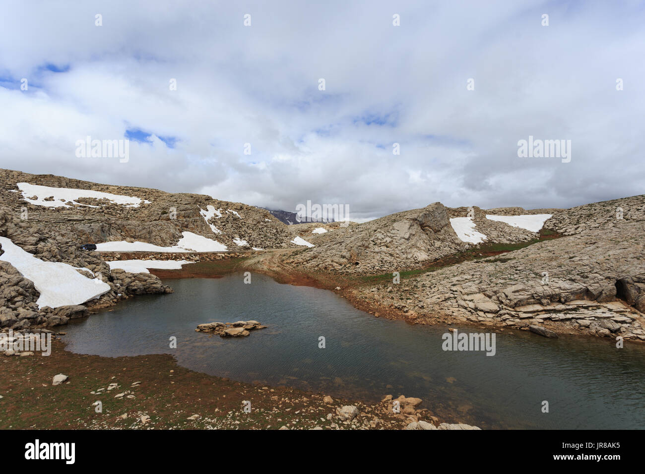 Horizontalen Schuss von Mountain Lake umgeben von Pisten fallenden Schnee schmelzen Stockfoto
