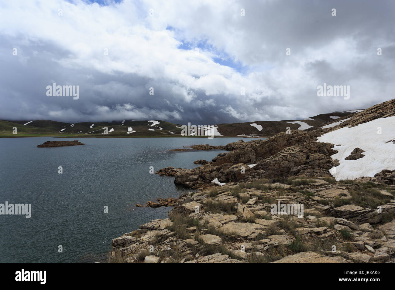 Horizontalen Schuss von Mountain Lake umgeben von Pisten fallenden Schnee schmelzen Stockfoto