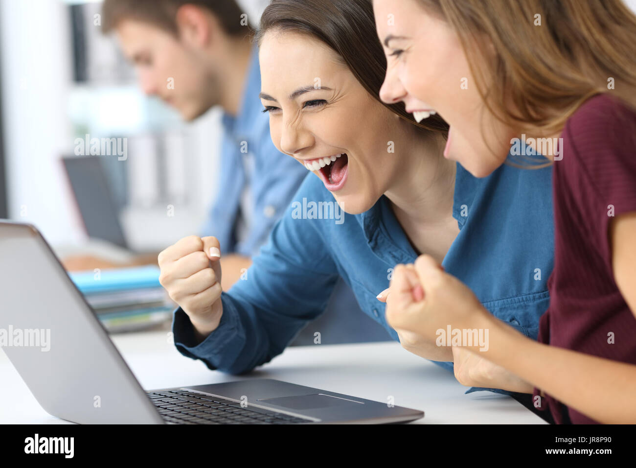 Zwei aufgeregt Geschäftsfrauen auf Linie News in einem Laptop im Büro lesen Stockfoto