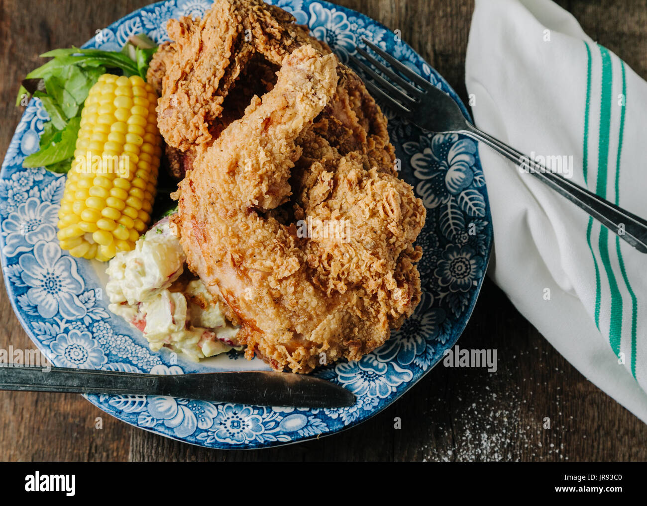 Buttermilch gebratenes Huhn mit Mais und Kartoffel Salat auf Holz- Oberfläche Stockfoto