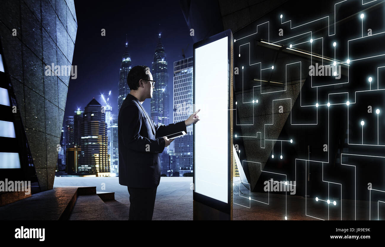 Intelligente Geschäftsmann berühren Sie den Bildschirm, die Informationen des intelligenten Kommunikationsnetz von Dingen zu suchen. Nachtaufnahme mit modernen Stadt Hintergrund Stockfoto