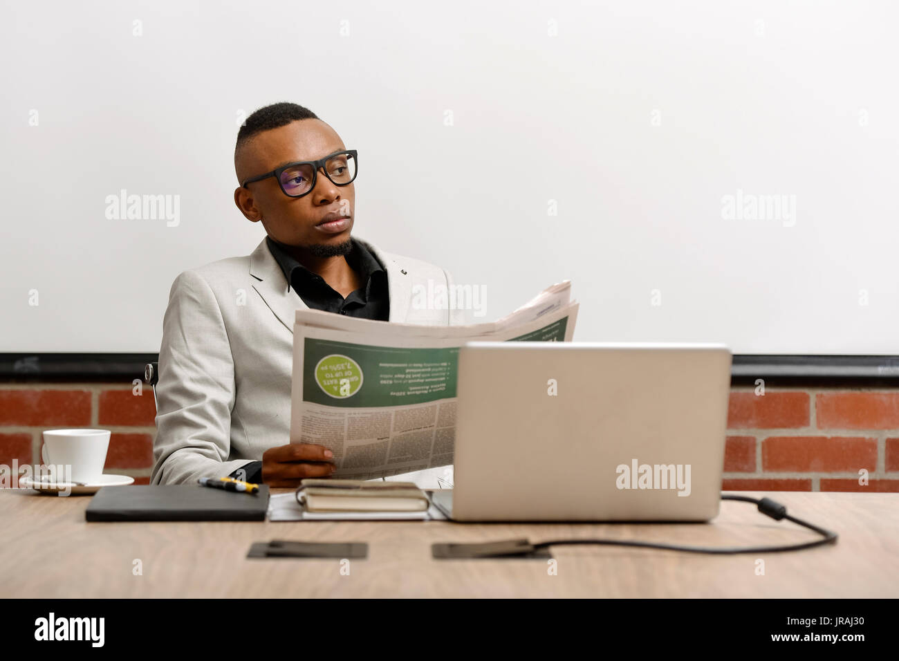 Young Business mann lesen Zeitung an seinem Schreibtisch Stockfoto