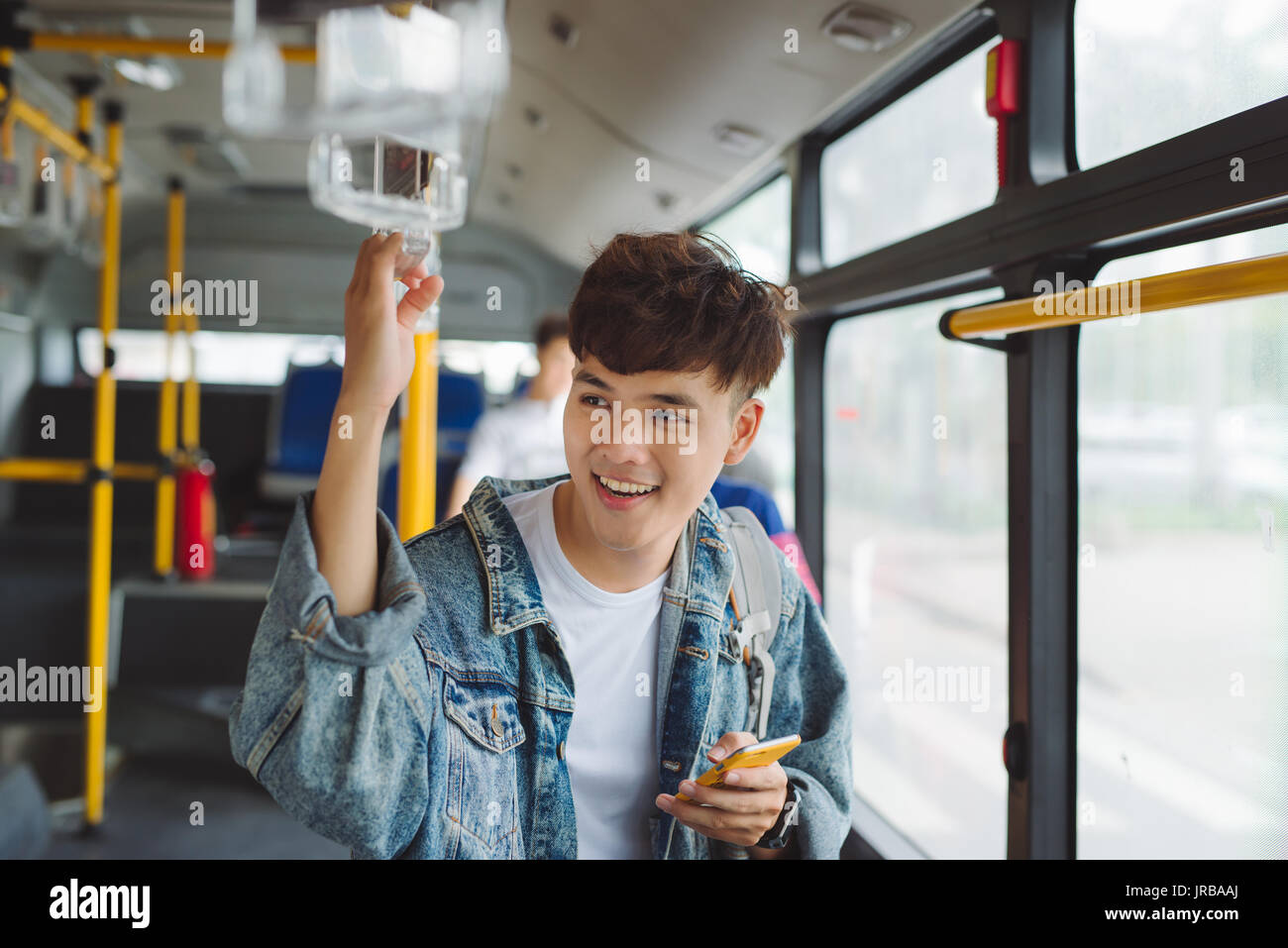 Schöner asiatischer Mann sitzt im Stadtbus und eine Nachricht auf dem Handy zu schreiben. Stockfoto