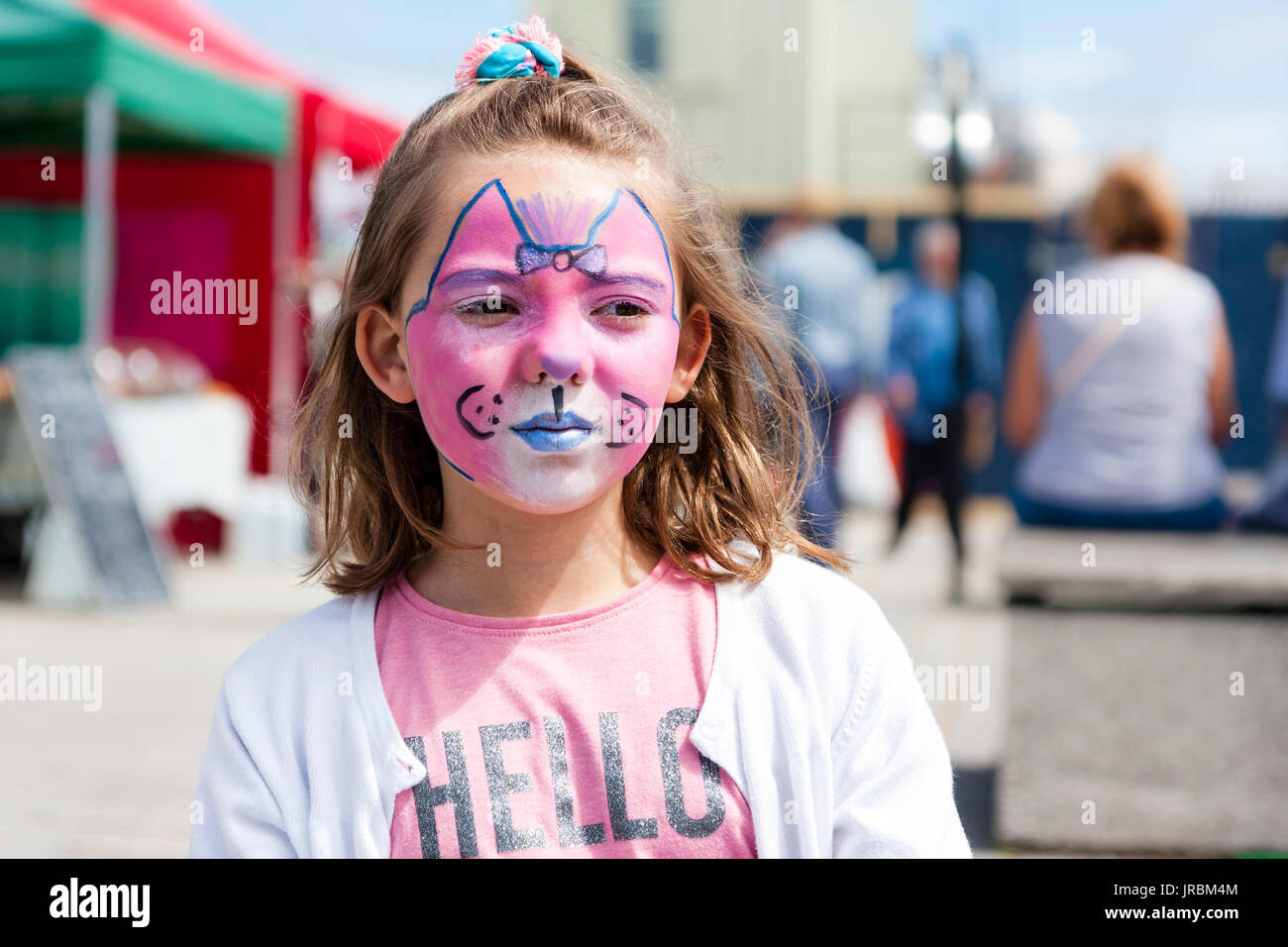 Kaukasier Kind, Mädchen, blond Haare, im Alter von 6-8 Jahren, Kopf, Gesicht gemalt mit Cat's Gesicht in Rosa und Blau. Im Freien. Denen aber kein Blickkontakt. Stockfoto