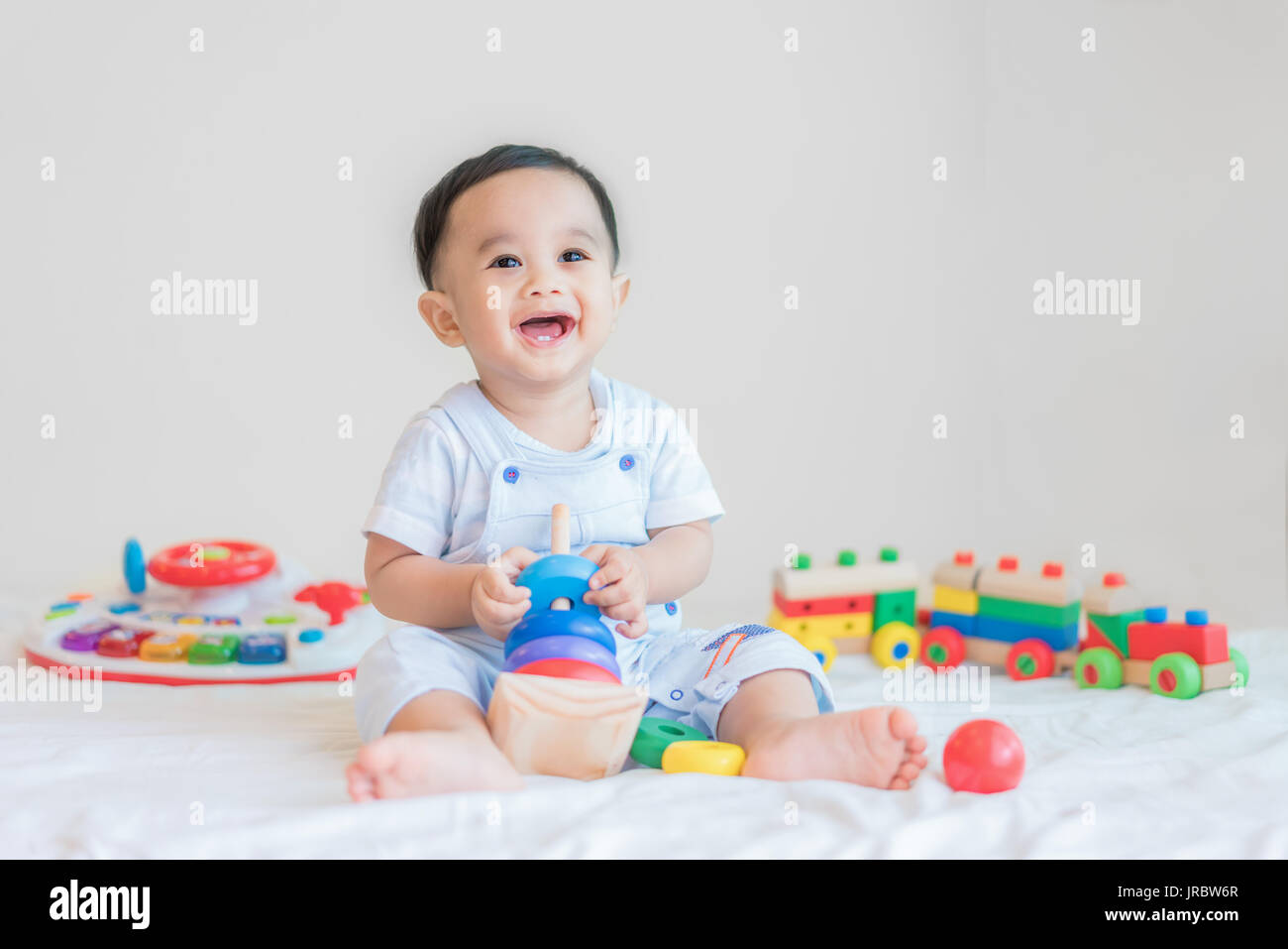 Entzückende asiatische Baby junge 9 Monate am Bett sitzen und spielen mit Farbe Entwicklungsstörungen Spielzeug zu Hause. Stockfoto