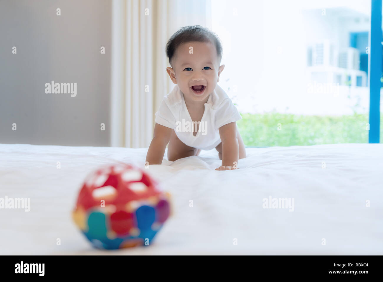 Crawling baby boy auf dem Bett im Schlafzimmer zu Hause und er lächeln Sie, Asiatische Baby. Stockfoto