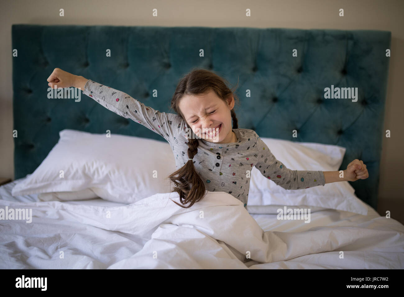 Mädchen recken ihre Arme beim Aufwachen in Schlafzimmer zu Hause Stockfoto