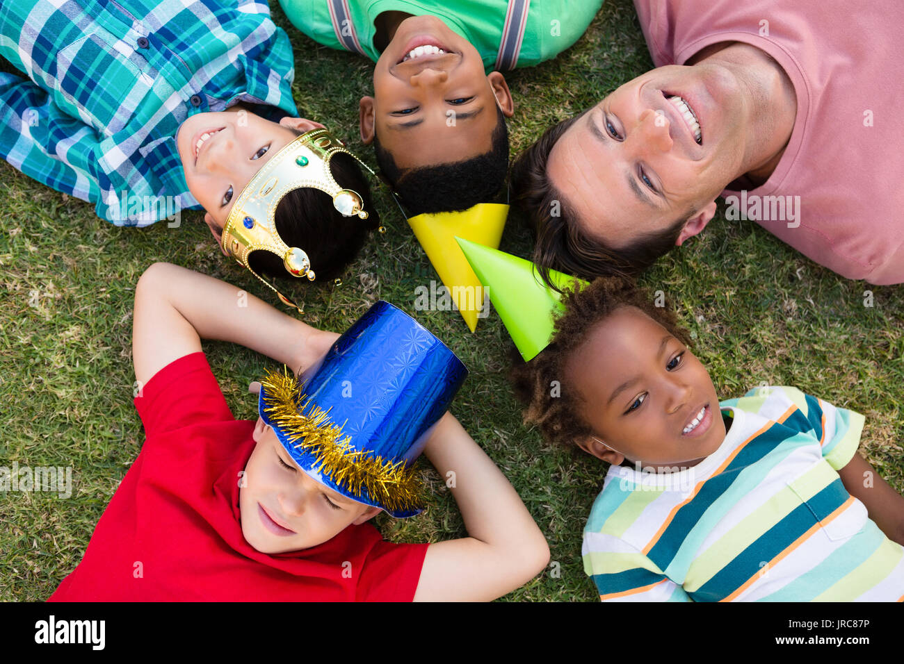 Direkt oberhalb der Mann mit Kindern liegen auf Feld während der Partei Stockfoto