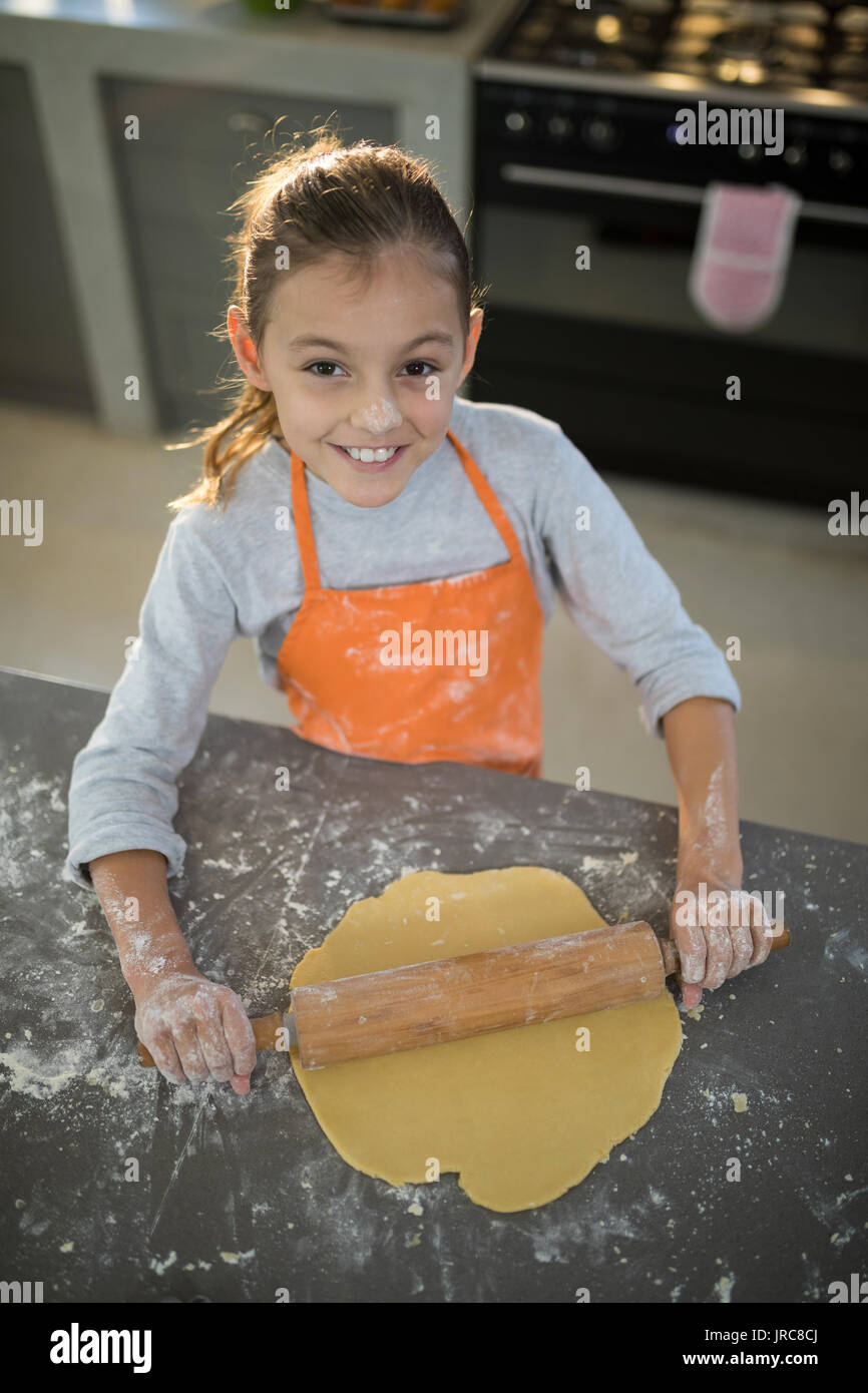 Portrait von kleinen Mädchen Abflachung Teig auf der Arbeitsplatte in der Küche Stockfoto
