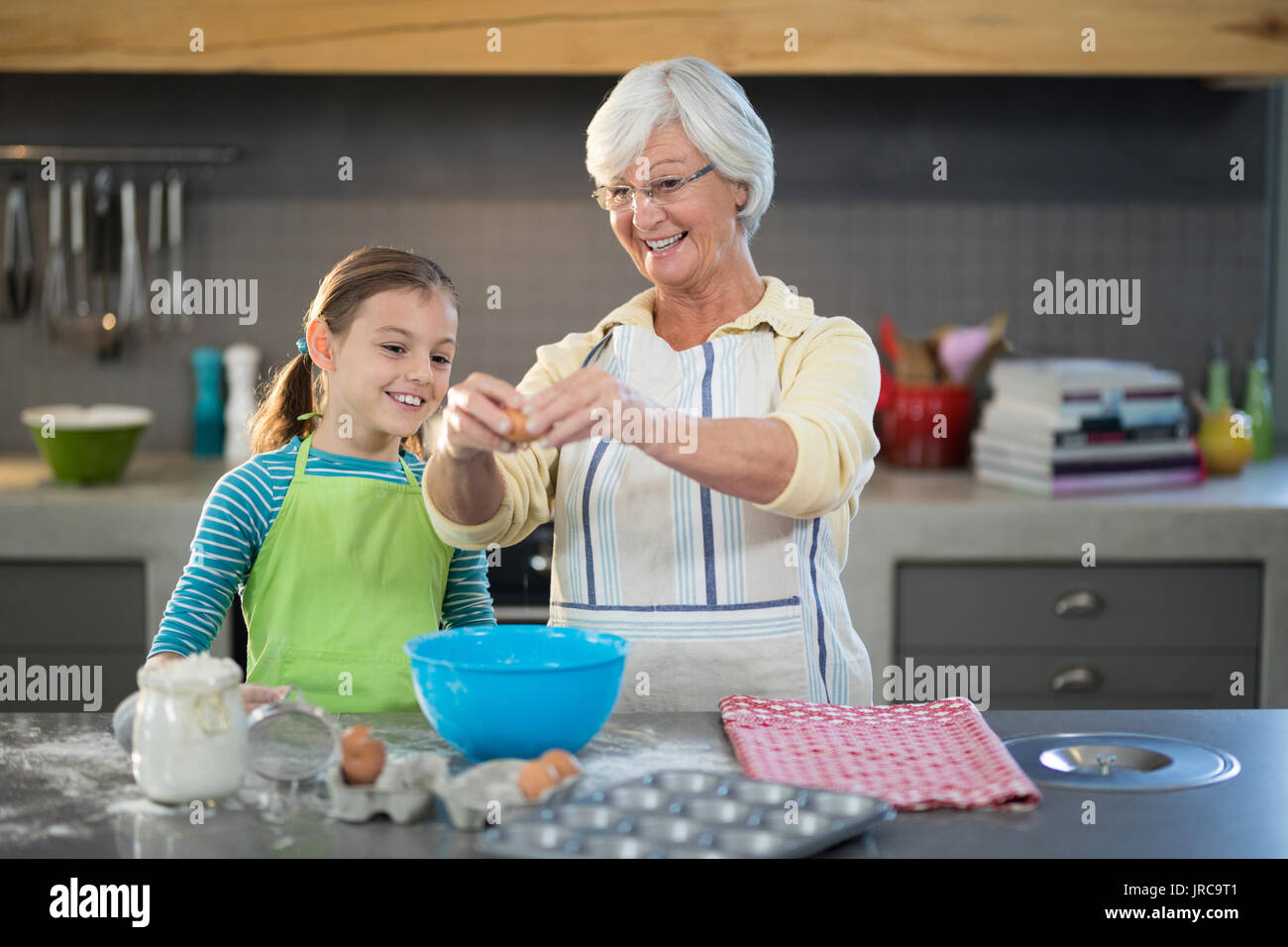 Lächelnde Großmutter, Enkelin Eier in der Küche zu brechen Stockfoto