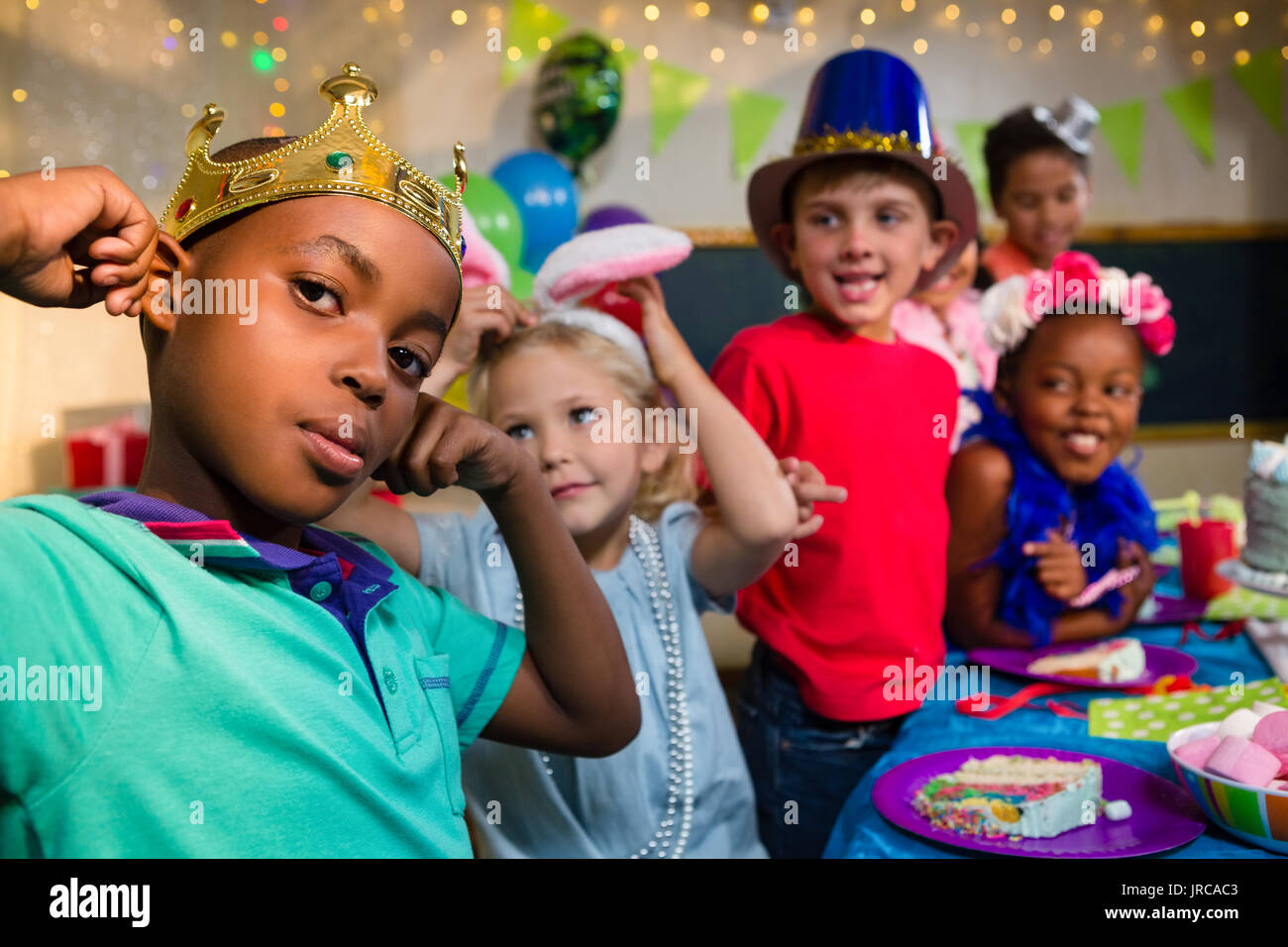 Verspielte Kinder am Tisch während Geburtstag Stockfoto