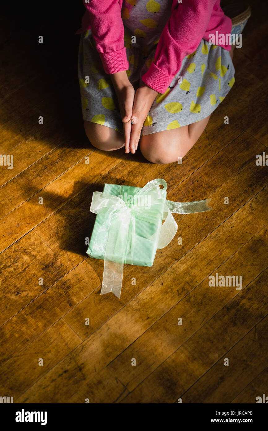 Mädchen sitzend mit Geschenkbox auf Holzboden zu Hause Stockfoto