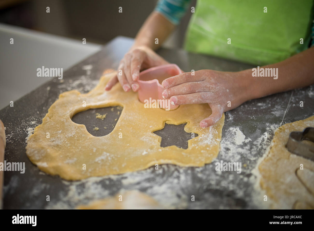 Mädchen schneiden Teig mit einem Ausstecher in der Küche Stockfoto