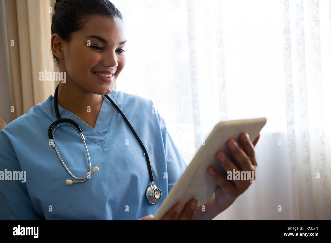 Lächelnd weibliche Arzt mit digitalen Tabelle im Ruhestand home Stockfoto