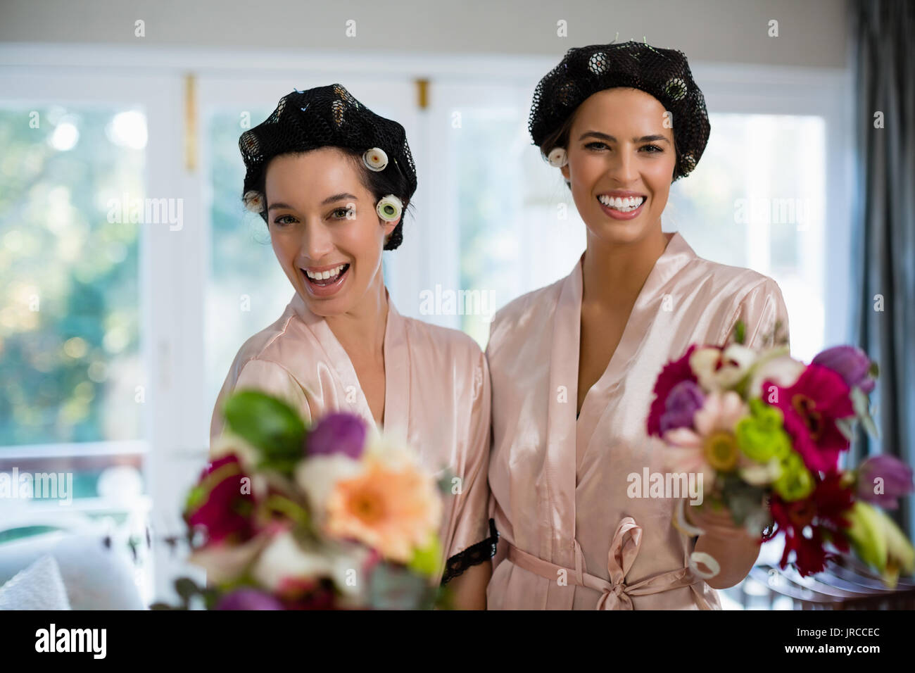 Portrait von Braut und Brautjungfern mit Blumenstrauß zu Hause stehend Stockfoto